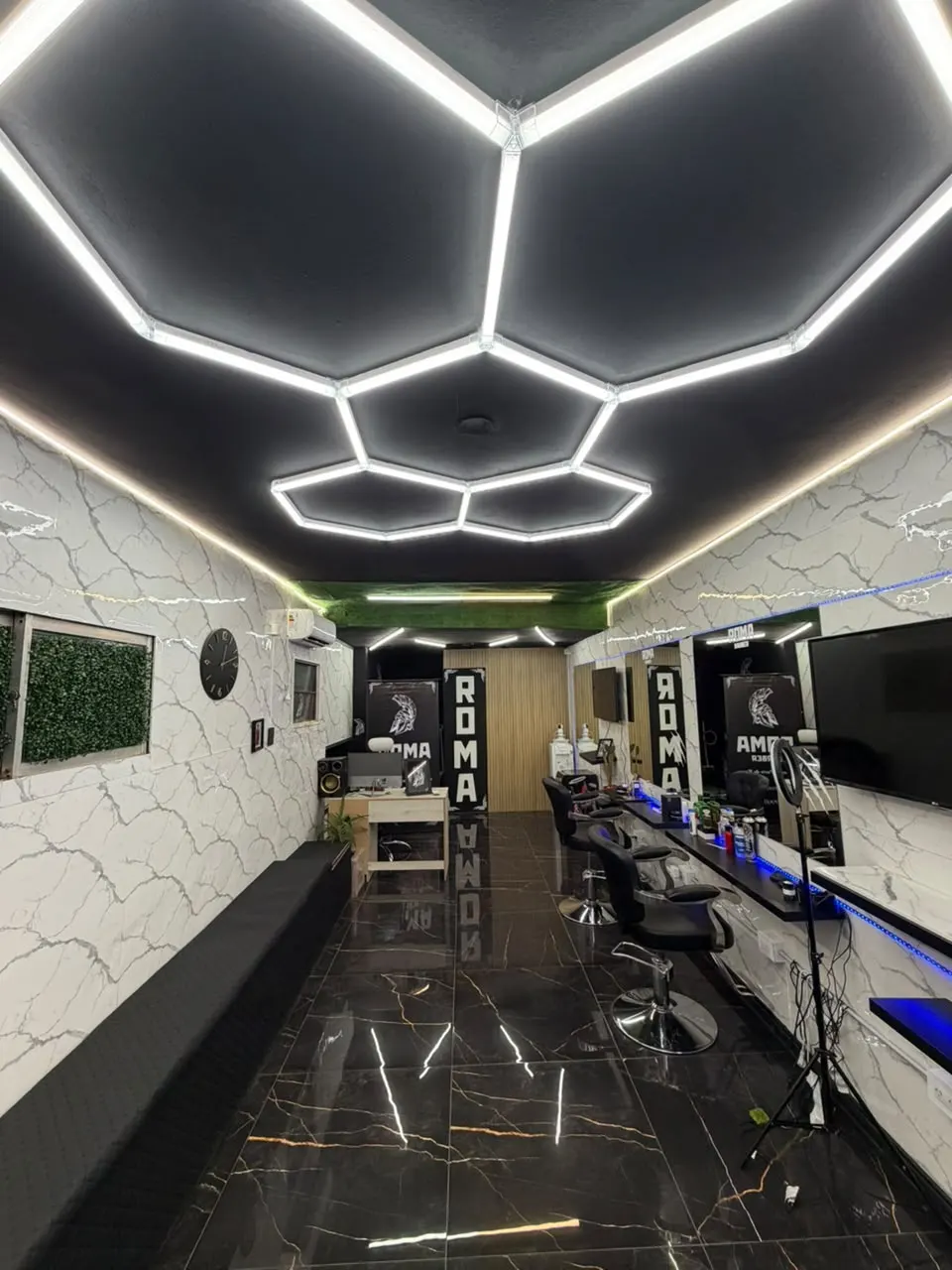 El salón de ROMA: techo negro con luces hexagonales, paredes de mármol y piso negro